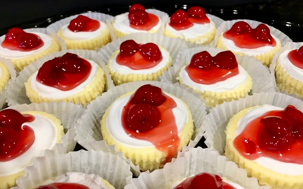 Mini cherry cheesecakes in paper cases, each topped with cherry compote