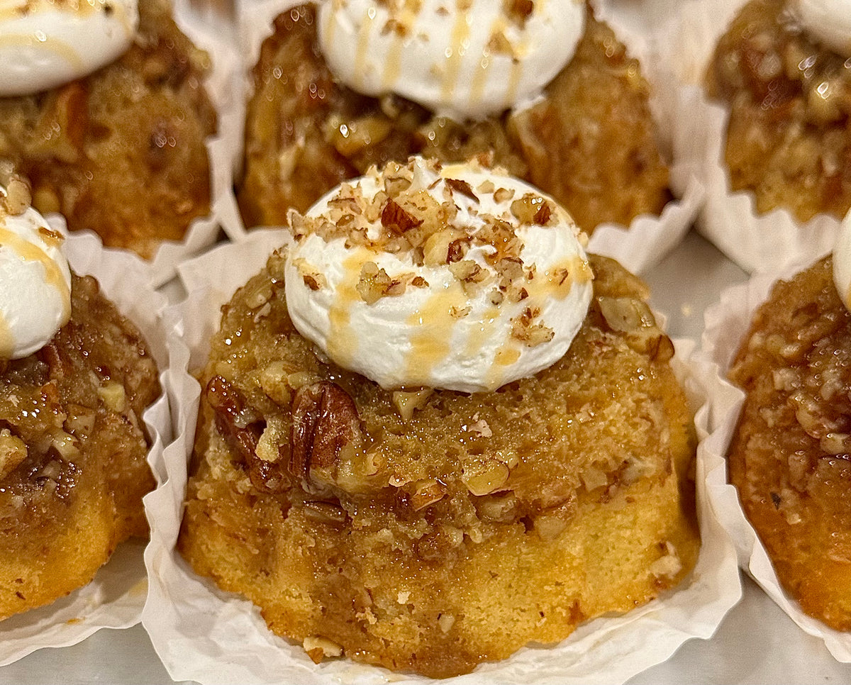 A mini caramel pecan cake topped with cream and chopped pecans